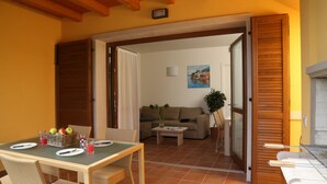 A dining area with wicker furniture, a table set for two, and a basket of fruit. - Residence Corte Leonardo (Garda)