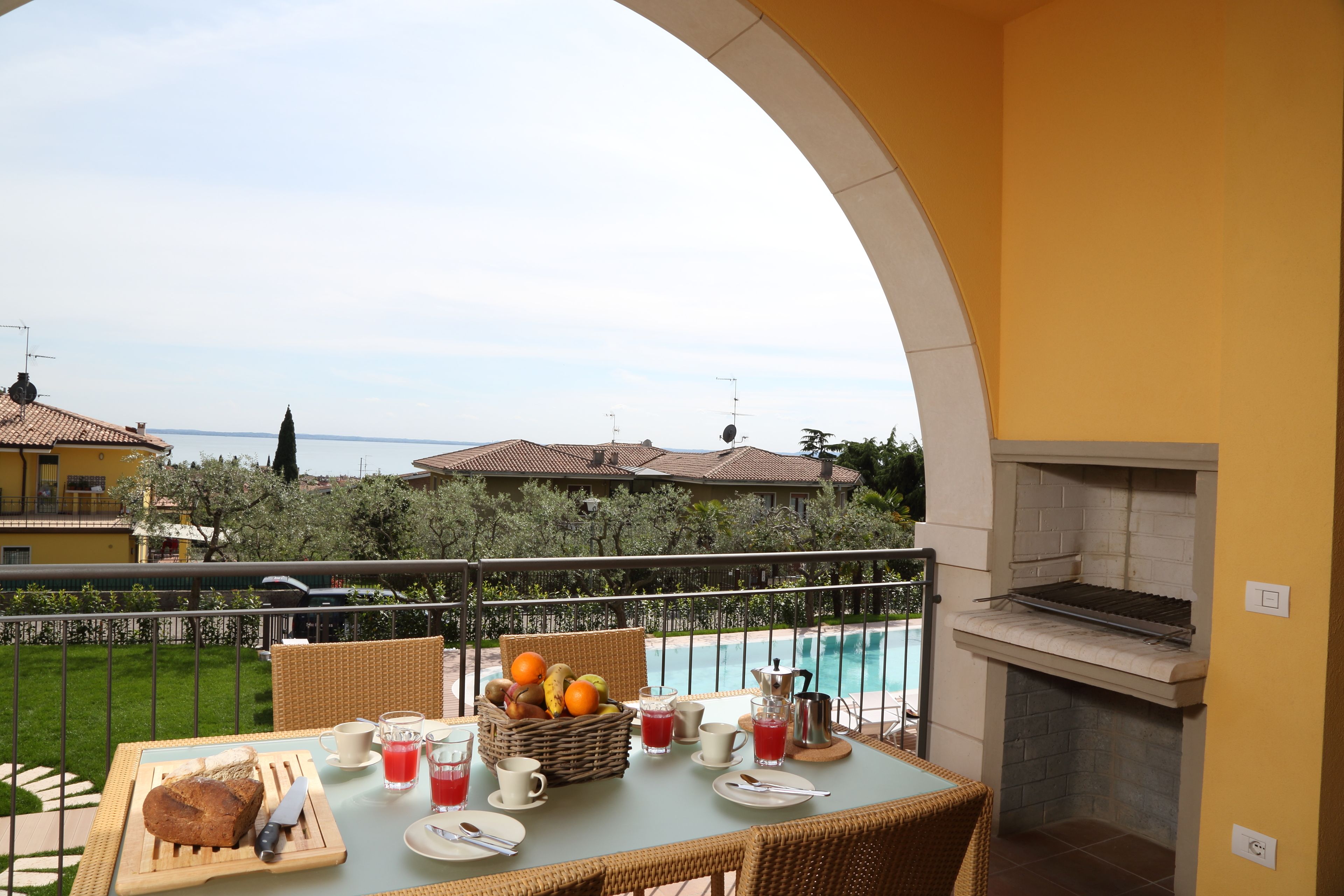Un balcón con una mesa dispuesta para el desayuno, una parrilla y vistas al mar.