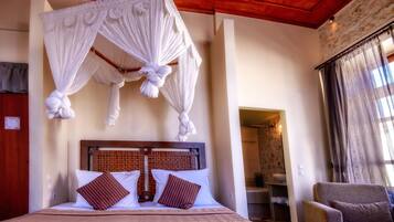 A bedroom with a canopy bed, wooden headboard, and a view of the bathroom.
