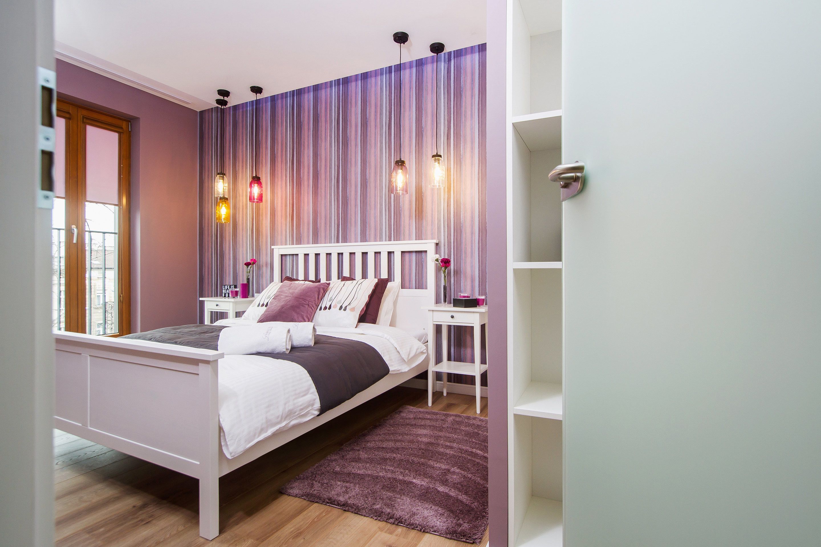 Un dormitorio con cama, mesitas de noche, una ventana y cortina a rayas.