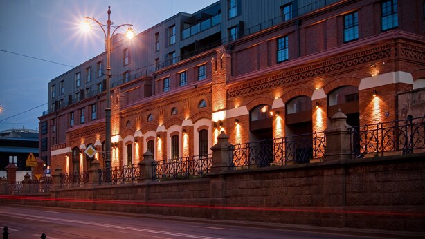 A multi-story building with a brick facade, arched windows, and a balcony with wrought iron railings. - Old Town Luxury Apartments by Amstra (Kraków)