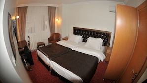 Une chambre d’hôtel avec un grand lit, un bureau avec une chaise, une armoire et une fenêtre avec des rideaux.