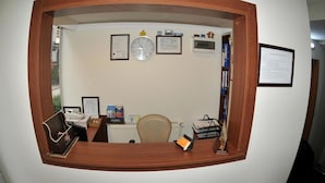 Un comptoir d’accueil avec une horloge, des certificats encadrés et un tableau d’affichage.