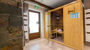 Un sauna avec une porte en bois, un banc et un porte-serviettes.