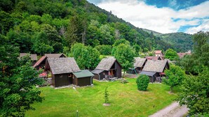 Un grupo de cabañas de madera con techos inclinados, rodeadas de exuberante vegetación y un paisaje montañoso.