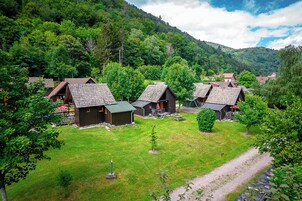 Un grupo de cabañas de madera con techos inclinados, rodeadas de exuberante vegetación y un paisaje montañoso.