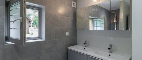 A modern bathroom with two sinks, a large mirror, and a window with frosted glass.