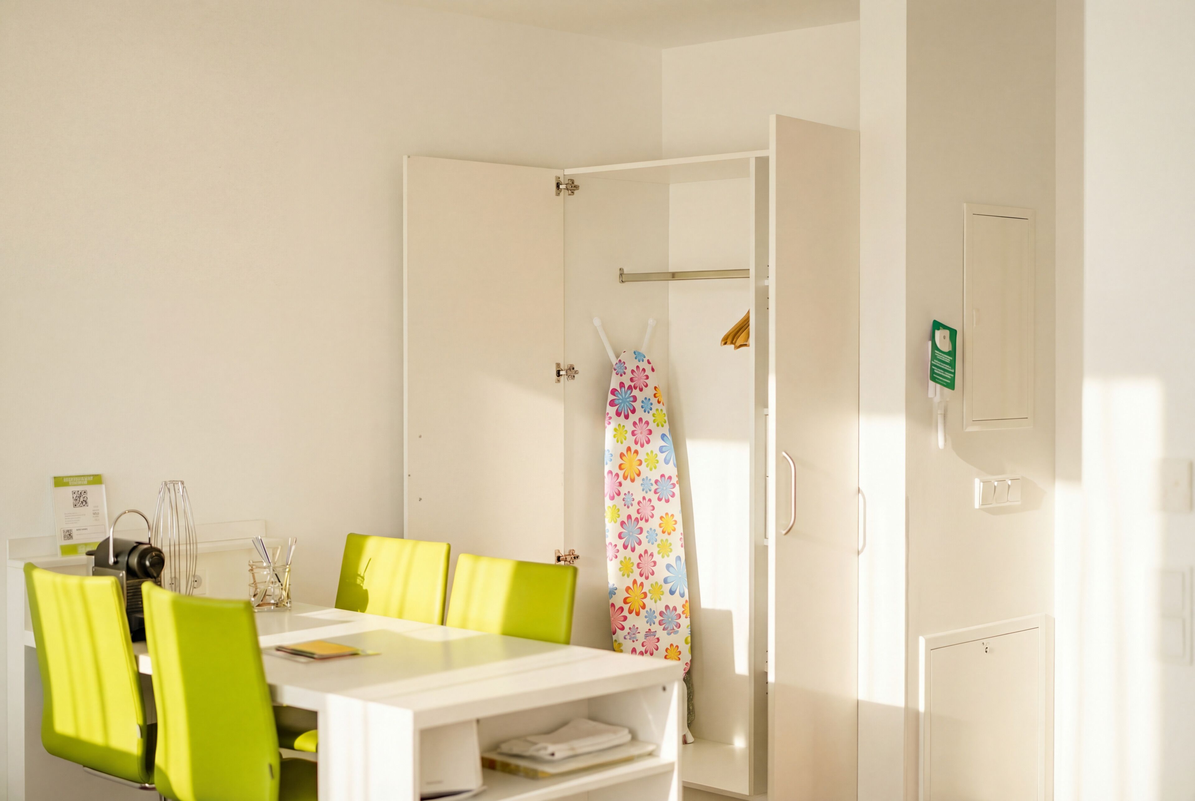 Ein Zimmer mit einem weißen Tisch, grünen Stühlen, einem Duschvorhang und einer Tür mit Griff.