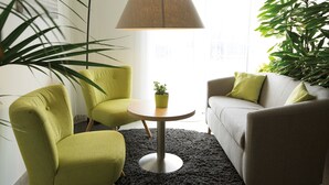 A living room with a round table, a sofa, and two chairs. - ADAPT APARTMENT HOTEL Berlin-Adlershof (Berlin)