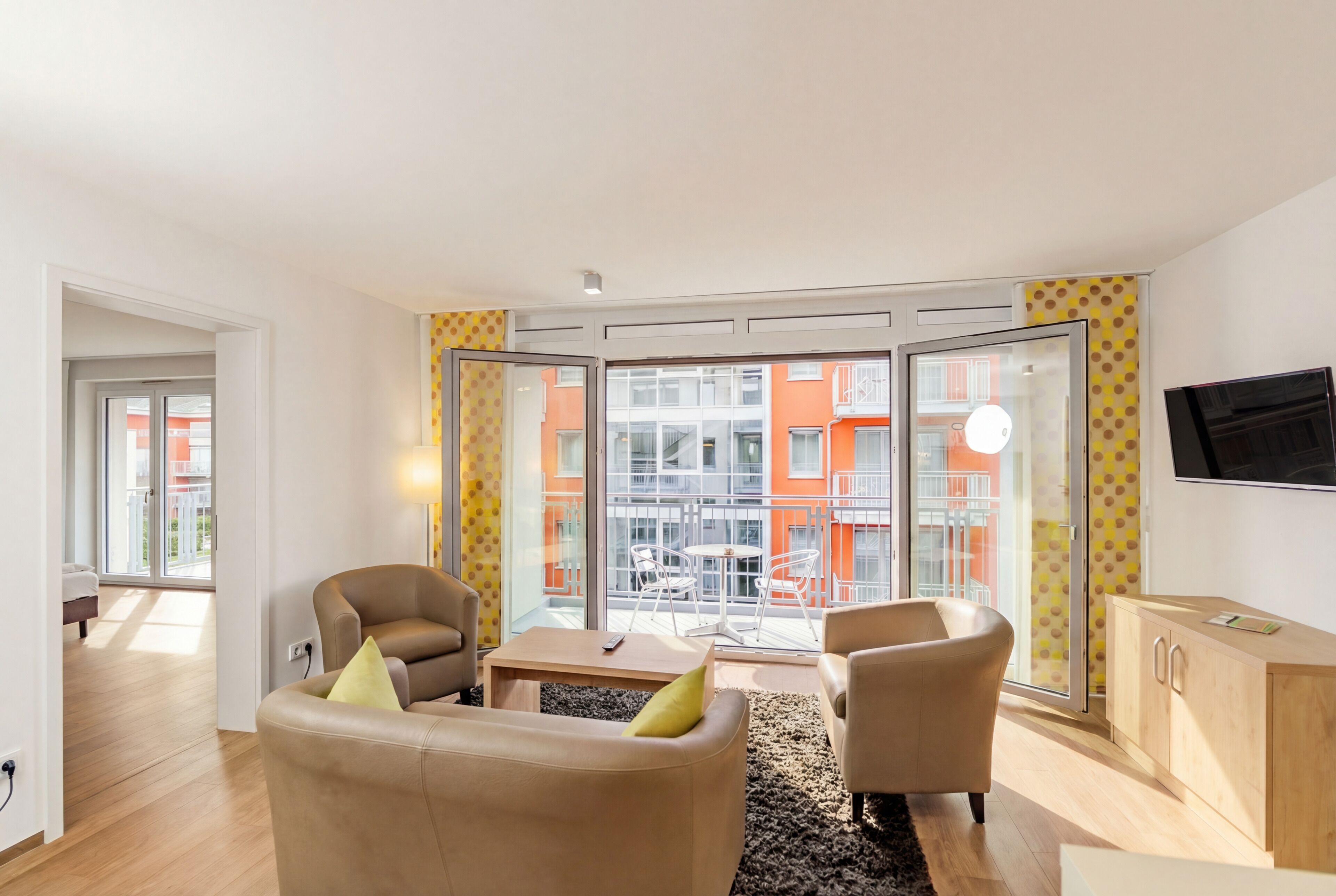 Ein modernes Wohnzimmer mit einer Couch, Sesseln, einem Couchtisch und einem Fernseher.