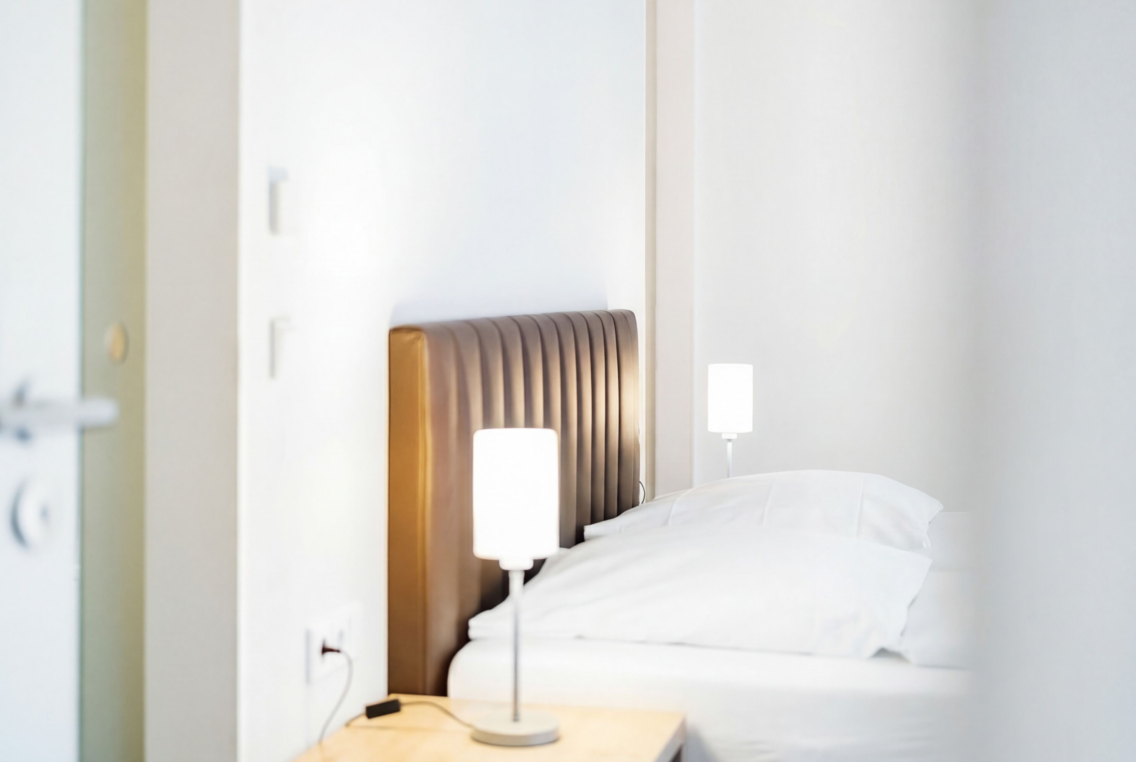 Ein Hotelzimmer mit Bett, Nachttisch, Lampe und Wandleuchte.