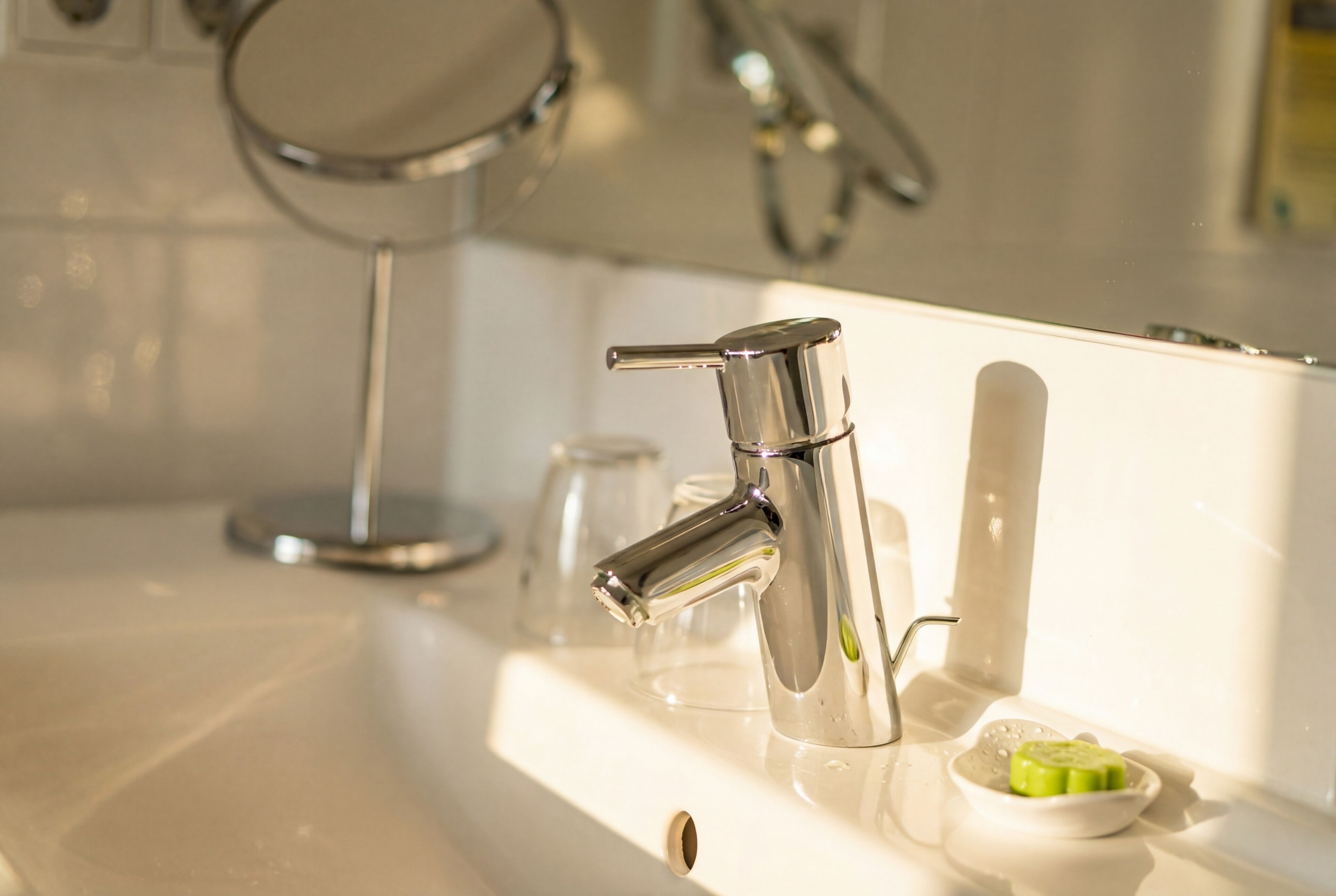 Un lavabo de salle de bain avec un robinet chromé, un miroir et un porte-savon.