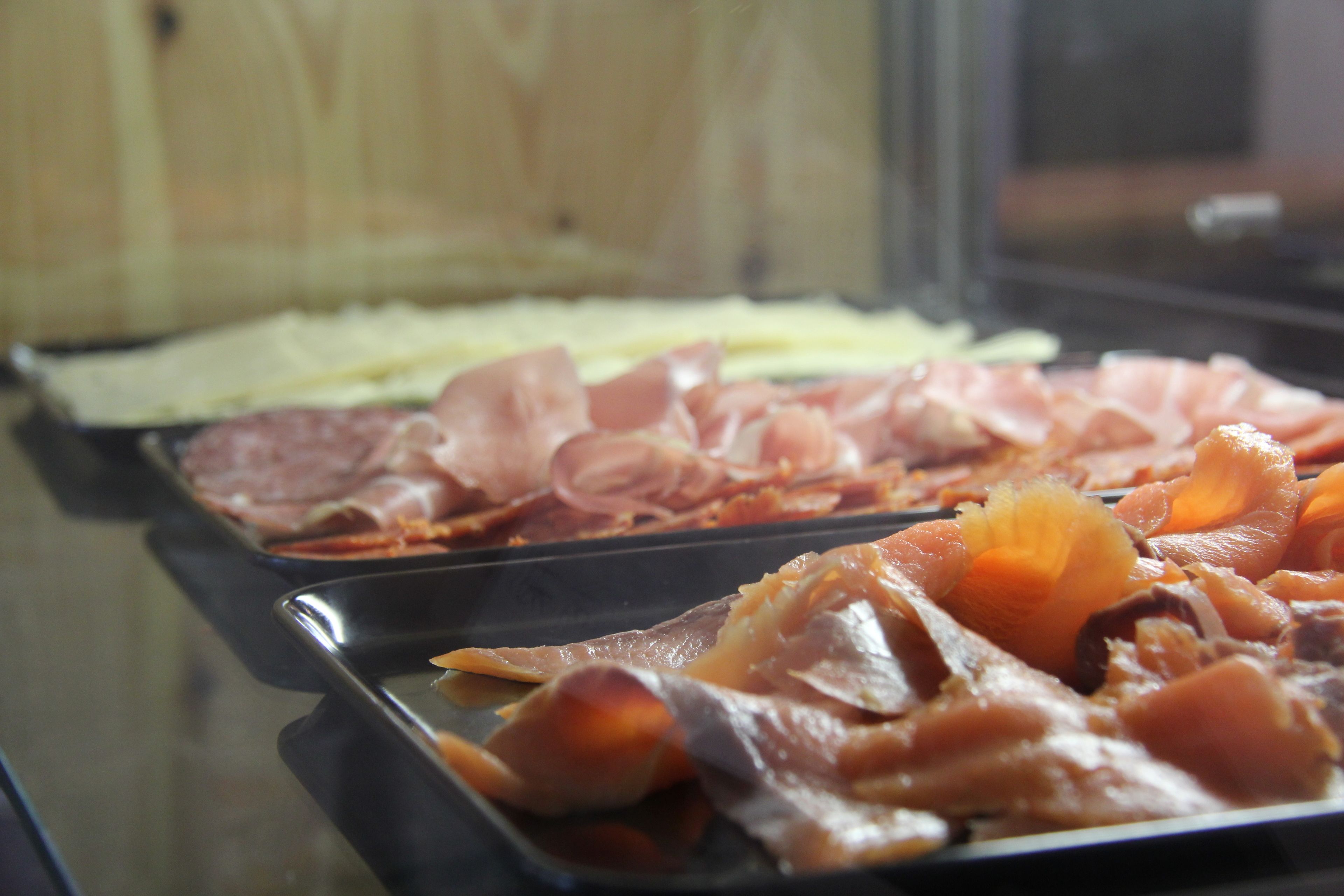 Un bufé con diferentes carnes y quesos.