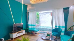 Una sala de estar moderna con un televisor de pantalla plana, un sofá, una silla, una mesa de centro y una planta en maceta.