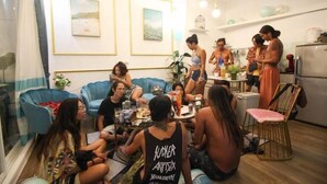 Un grupo de personas en una sala de estar moderna con un sofá, una mesa de comedor y una zona de cocina.