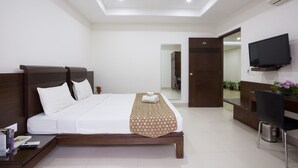 Una habitación de hotel moderna con una cama grande, un televisor de pantalla plana montado en la pared y una mesita con un control remoto.