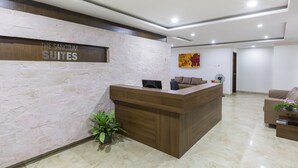 Un área de recepción con pared de piedra, mostrador de madera, un sofá y un ventilador.