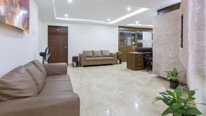 Un salón con un sofá color beige, un mueble de madera y una planta en maceta.