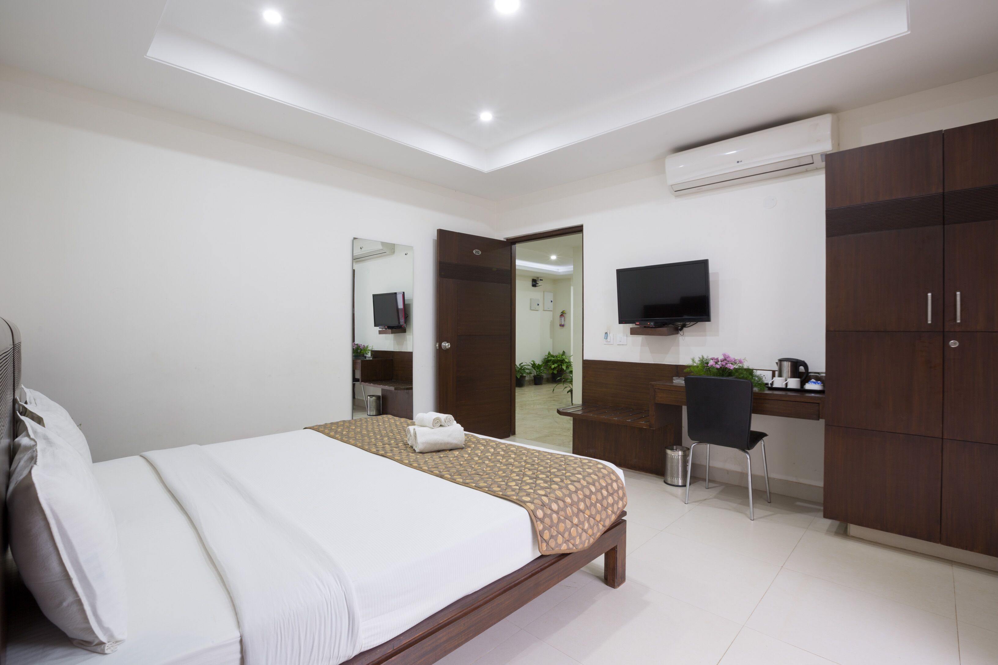 Una camera d'albergo moderna con un letto grande, una scrivania con una sedia, una televisione e un armadio.