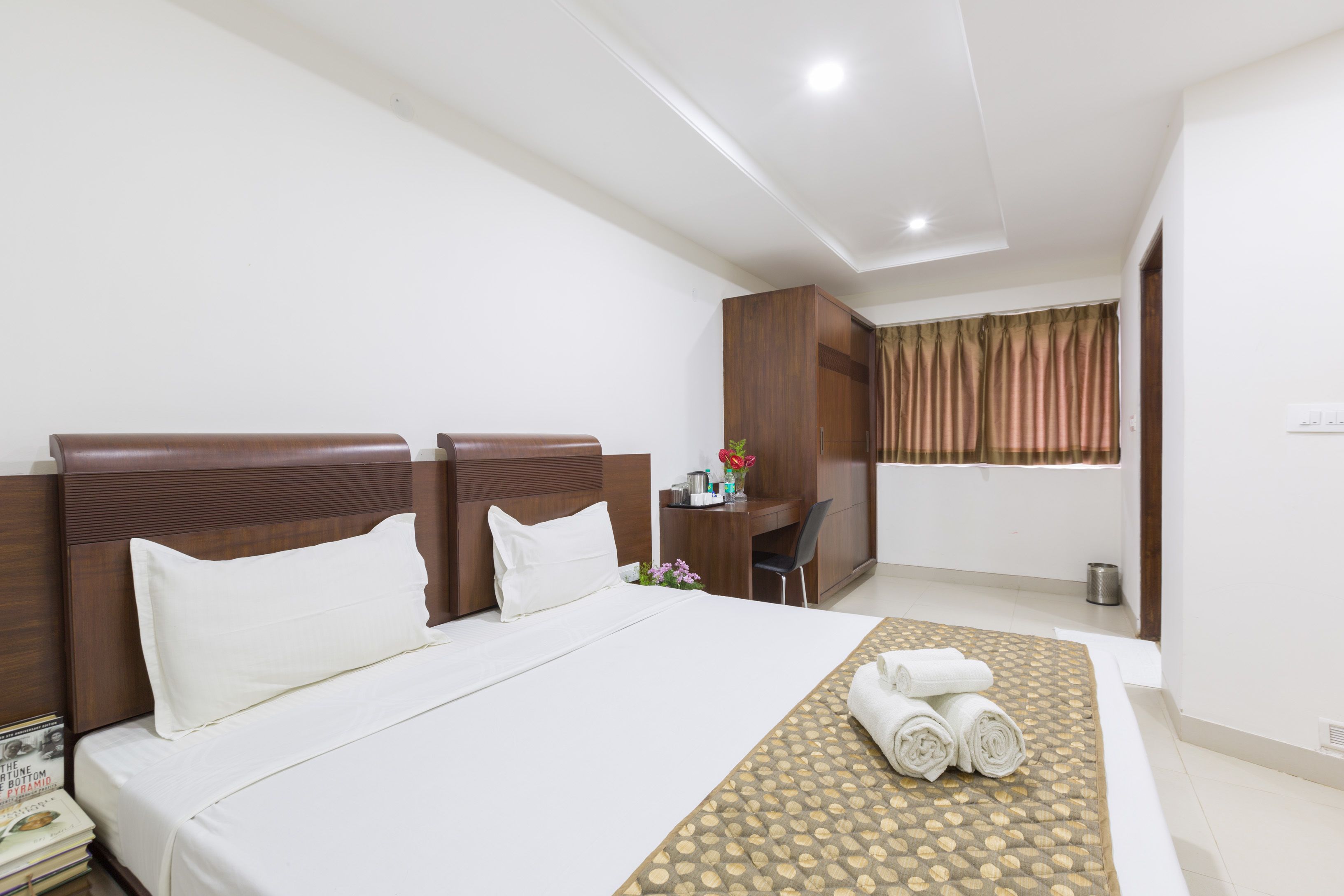 A hotel room with a large bed, a desk, and a shower area.