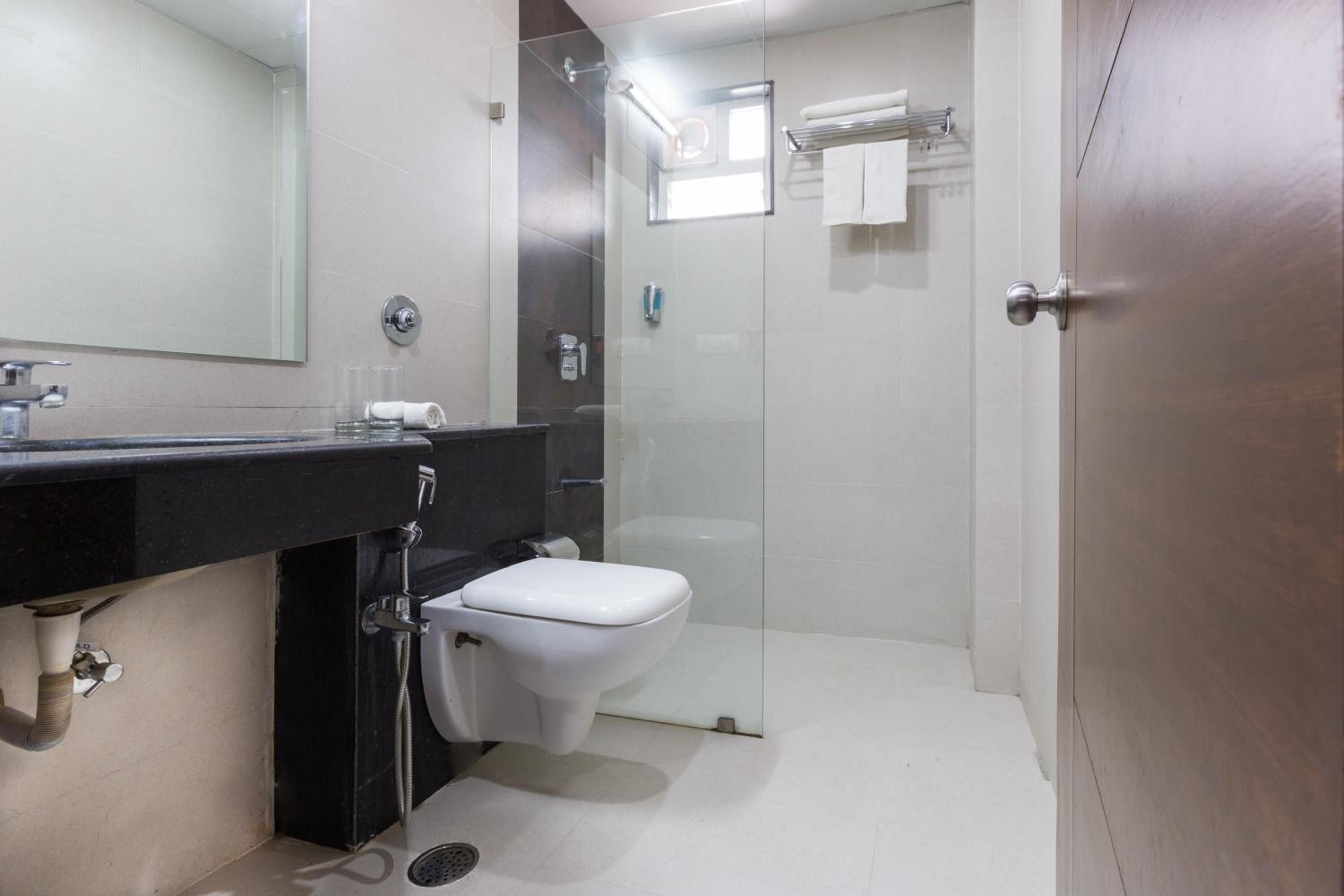 A modern bathroom with a black countertop, white toilet, and a glass-enclosed shower area.