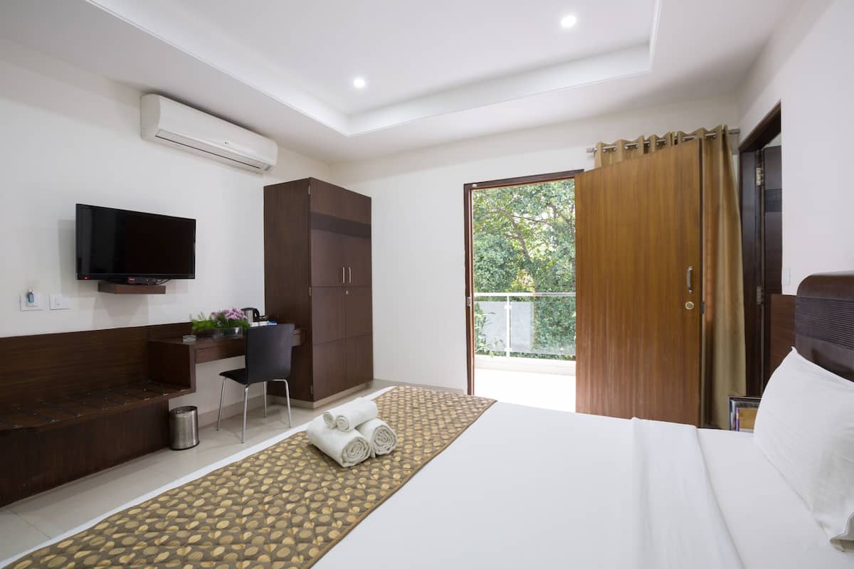 Ein modernes Hotelzimmer mit Bett, Schreibtisch, Fernseher und einem Balkon mit Blick.