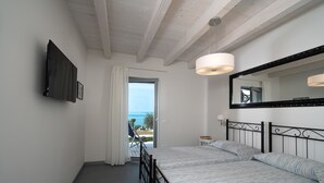 Ein Schlafzimmer mit Bett, einem großen Spiegel, einem Deckenventilator und Blick ins Freie.