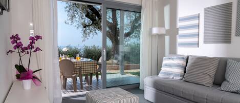 Una sala de estar moderna con un sofá gris, un reposapiés estampado y un comedor con mesa y sillas.