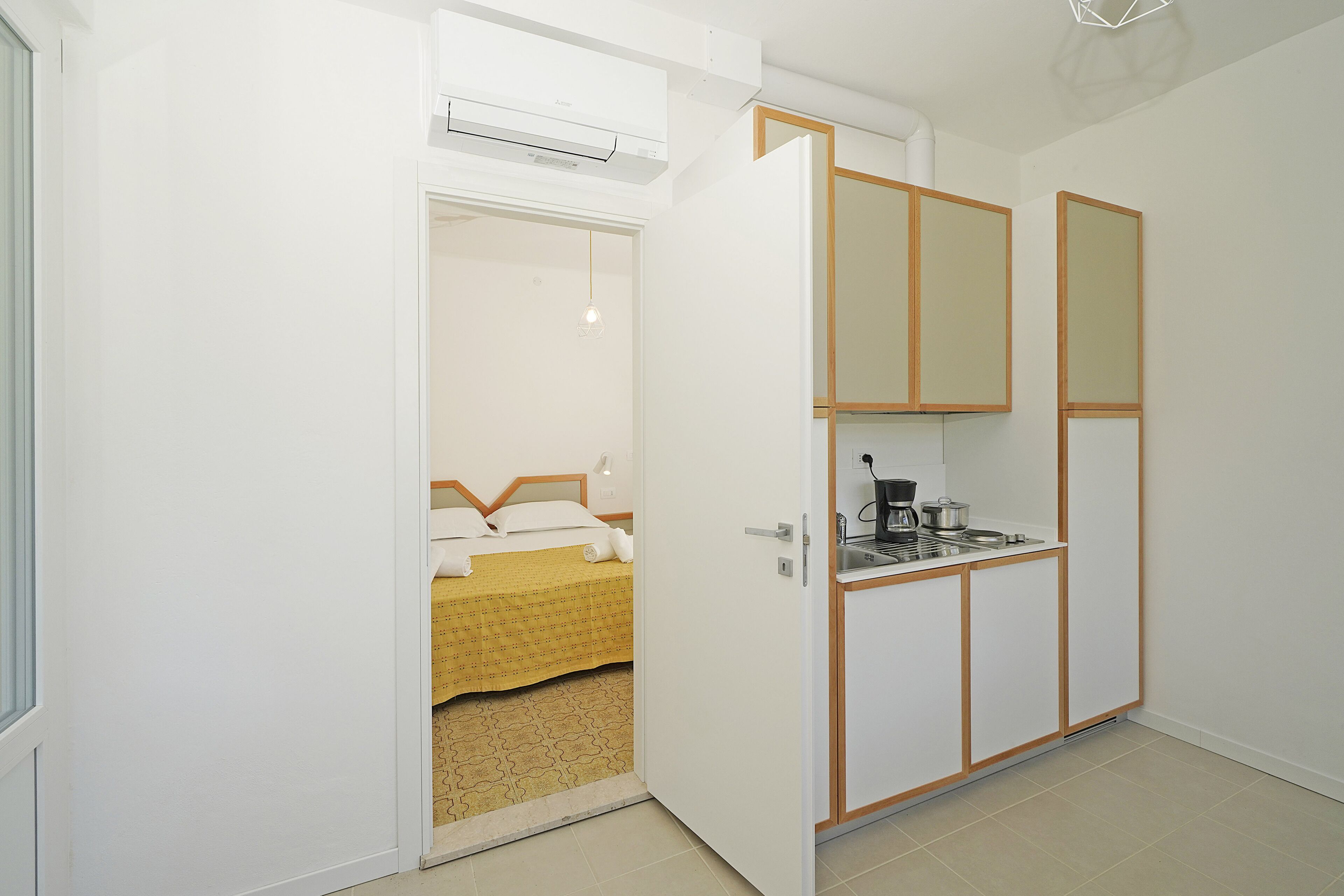Une petite chambre comprenant un lit, un coin cuisine et une armoire.