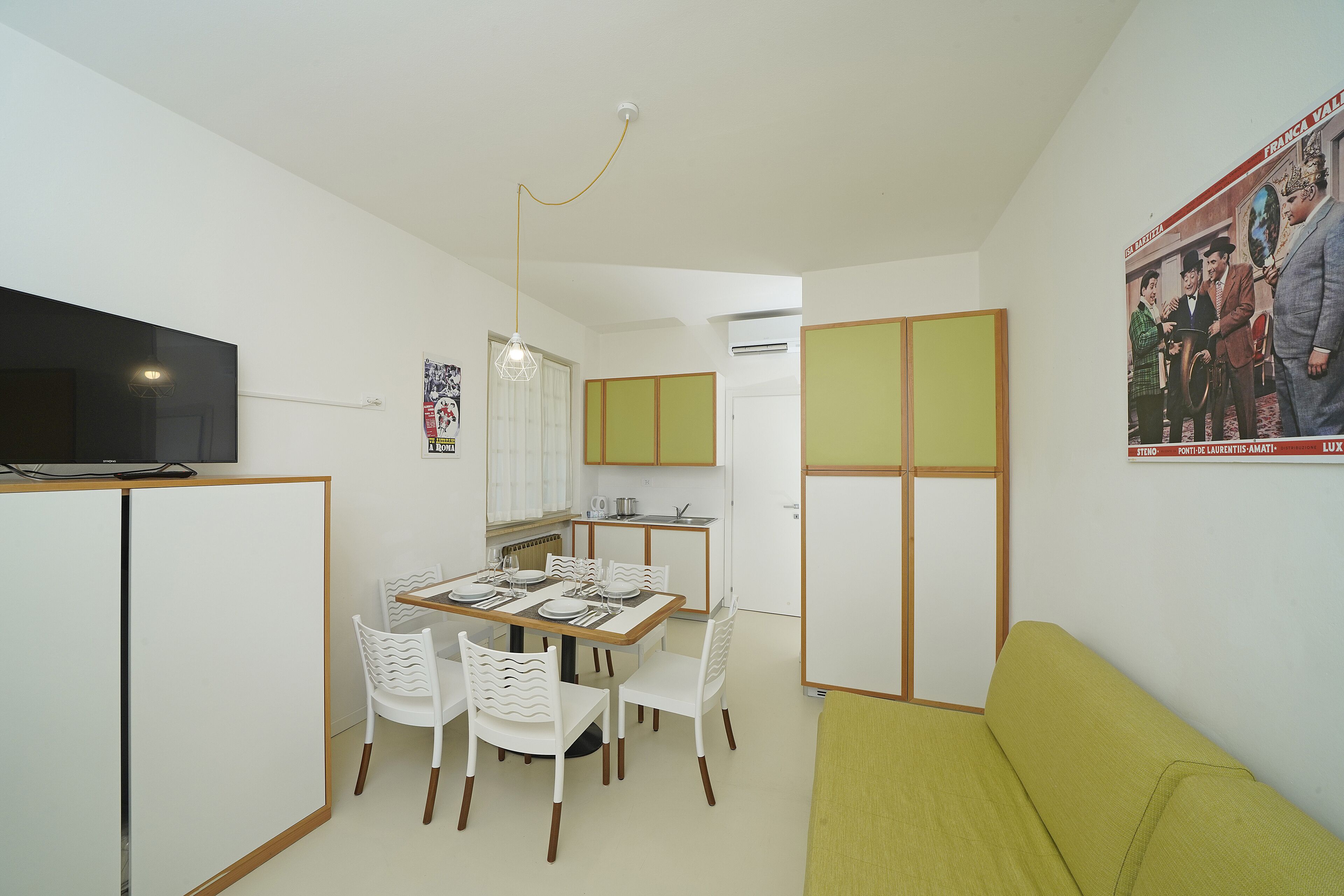 A compact living space with a dining area, kitchenette, and a green sofa.