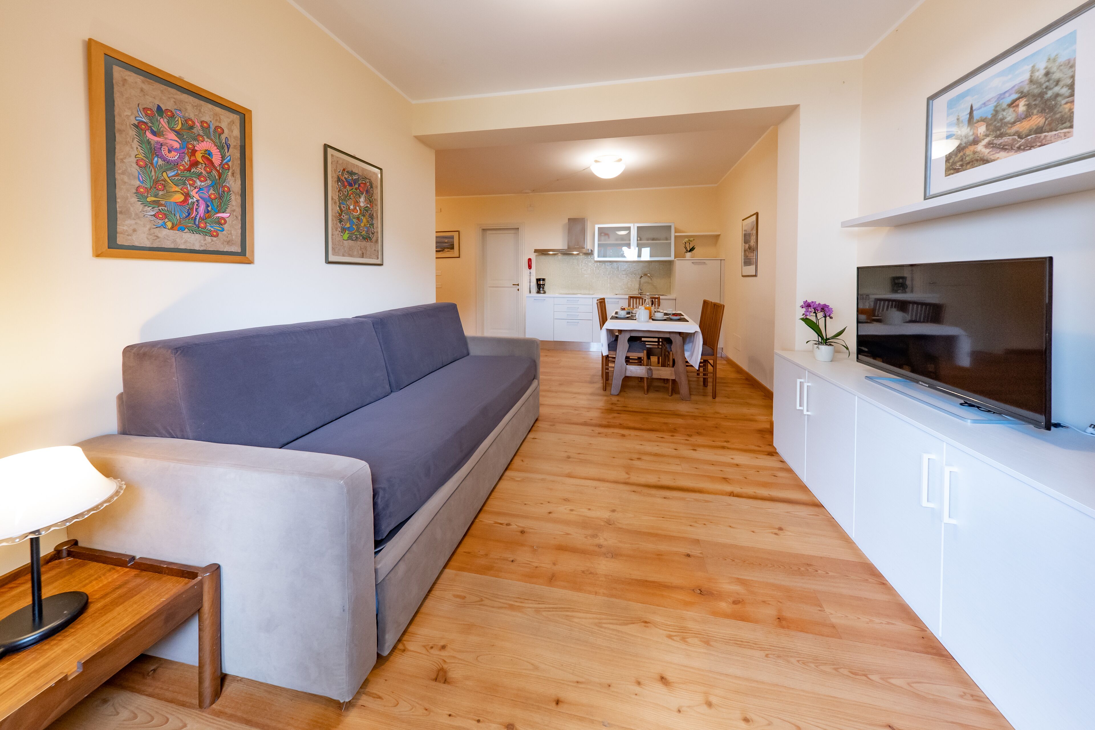 Ein modernes Wohnzimmer mit einer Couch, einem Fernseher und einem Essbereich mit Tisch und Stühlen.