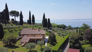 Eine Villa im mediterranen Stil mit einem Ziegeldach, umgeben von üppigem Grün und hoch aufragenden Zypressen.