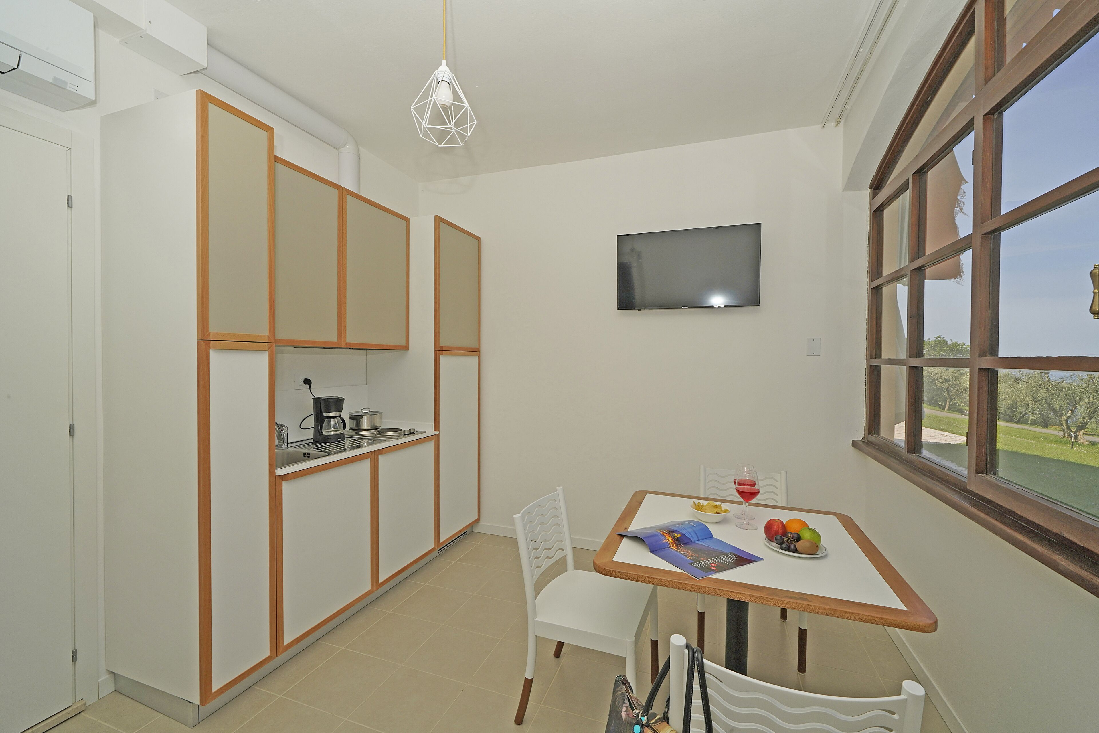 Cocina compacta con comedor, televisor montado en la pared y ventana con vistas.