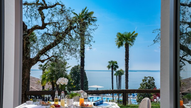 Ein Esstisch mit Frühstücksausstattung und Blick auf das Meer und den Pool.