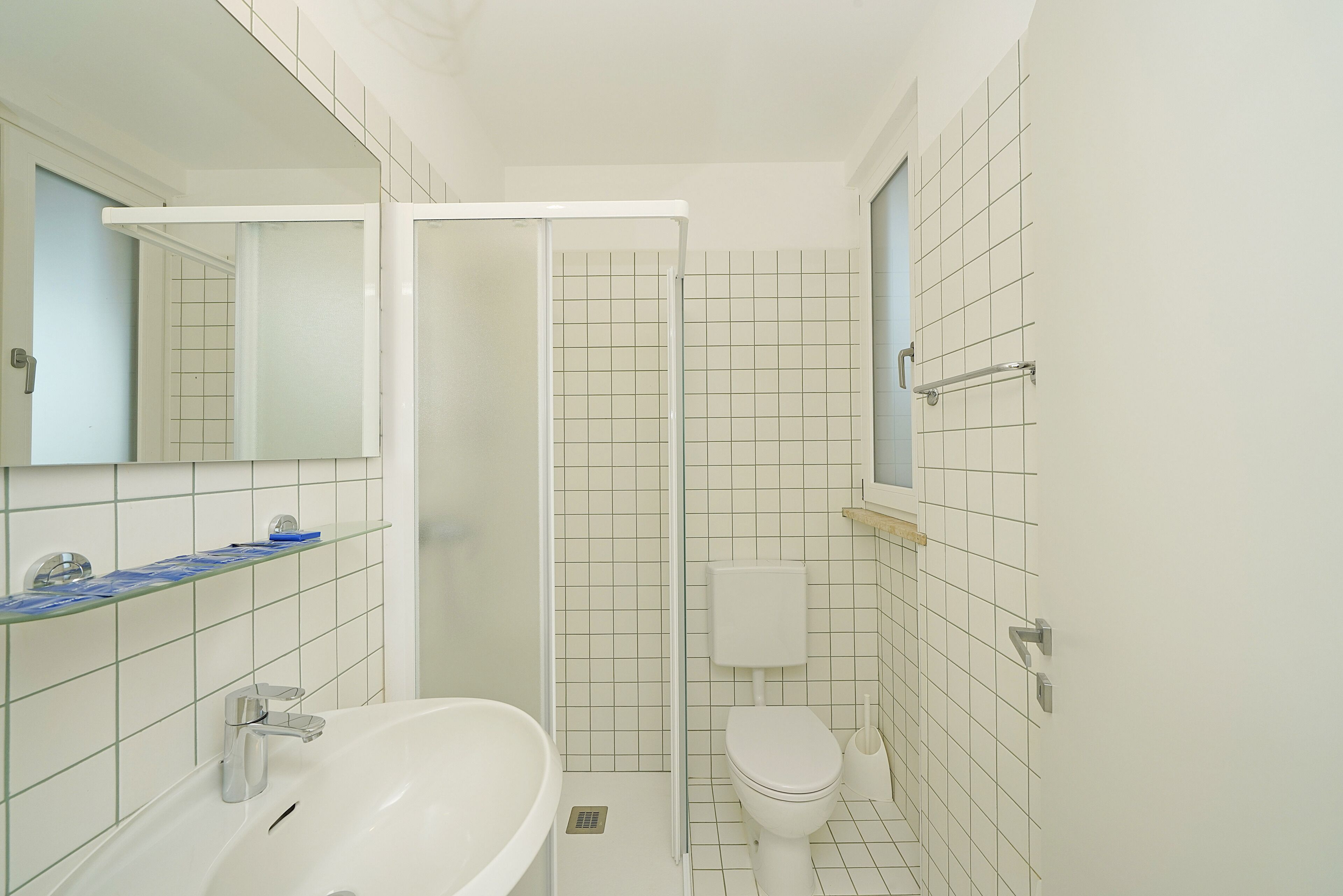 Un baño con lavamanos, inodoro y ducha blancos.