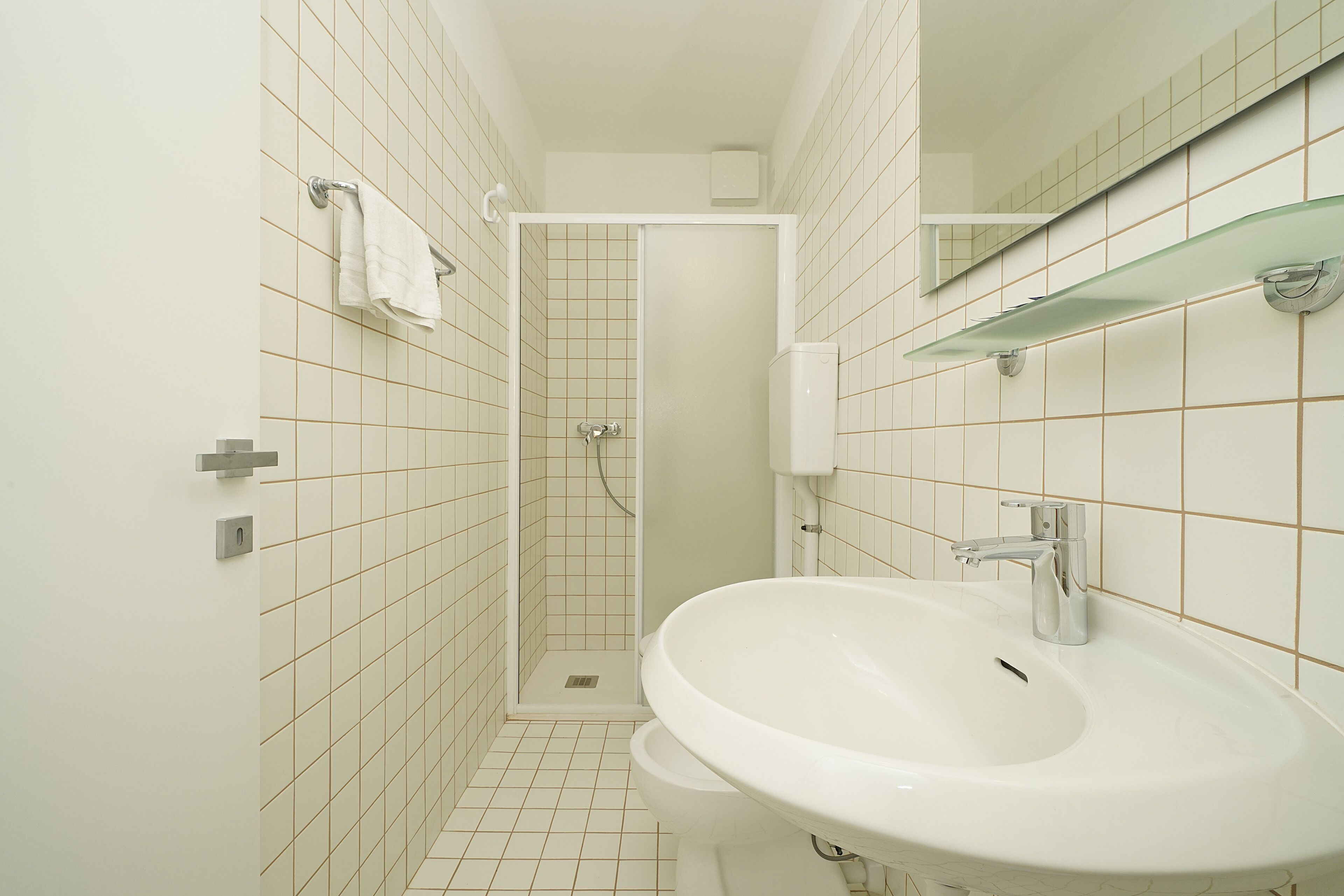 Un bagno con un lavandino bianco, cabina doccia in vetro e un water.