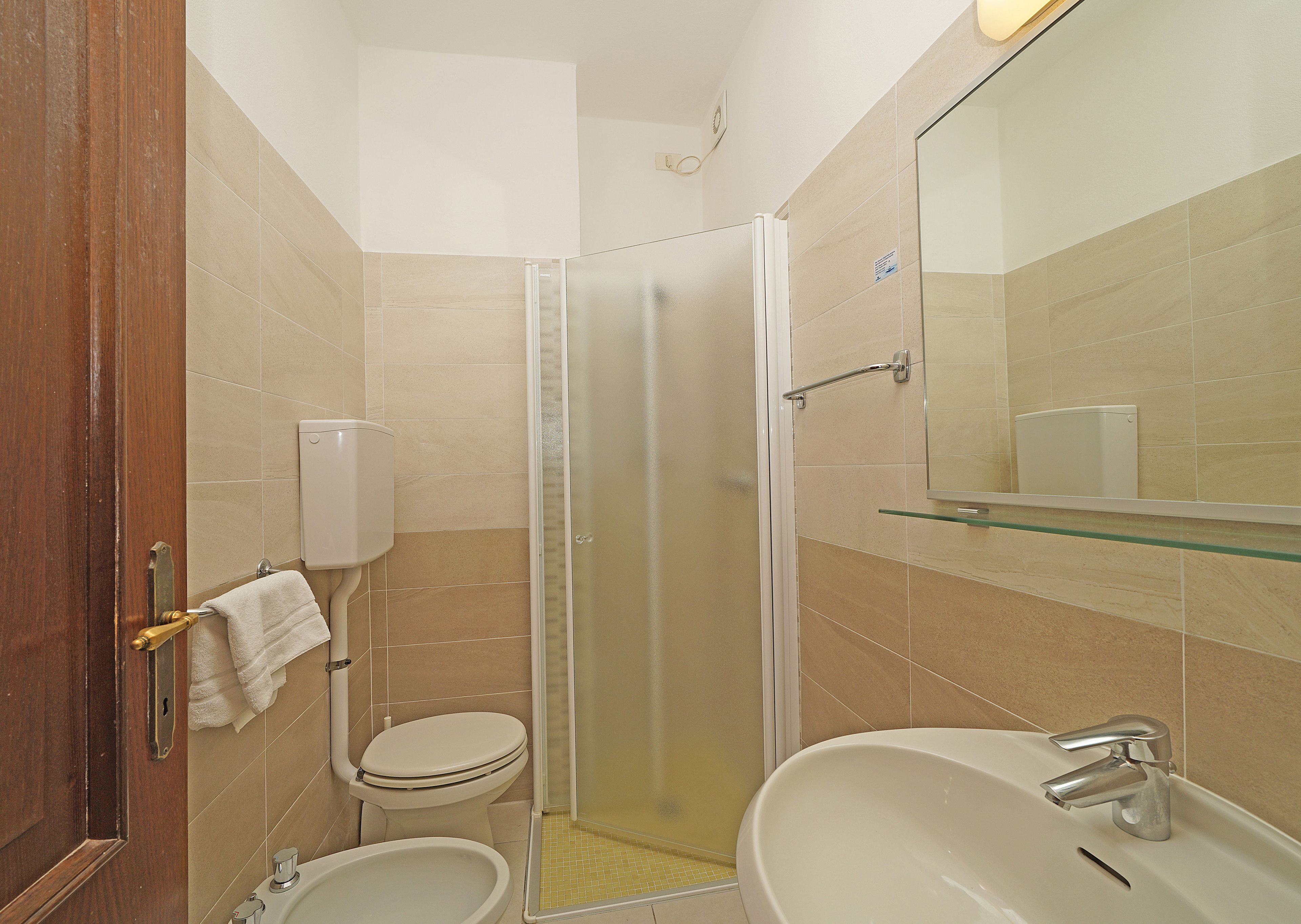 A bathroom with a toilet, sink, and glass-enclosed shower.