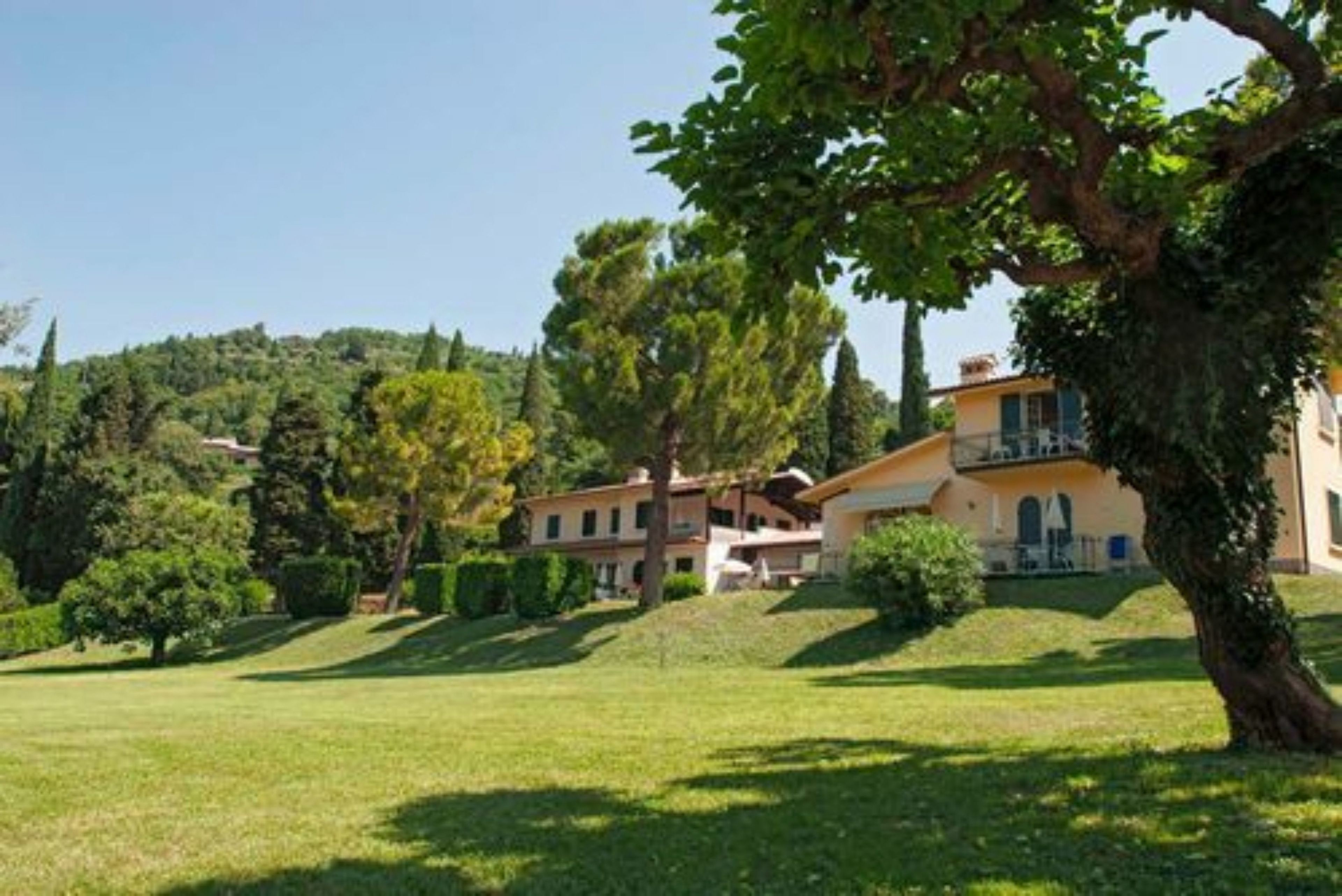 A villa with a large lawn, multiple buildings, and trees.