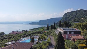 Ein Hotel an der Küste mit Schwimmbad, Tennisplatz und Blick auf Meer und Berge.