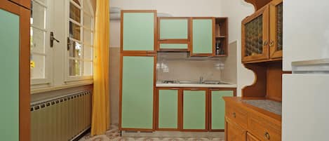 A compact kitchen with a radiator, a sink, and wooden cabinets.