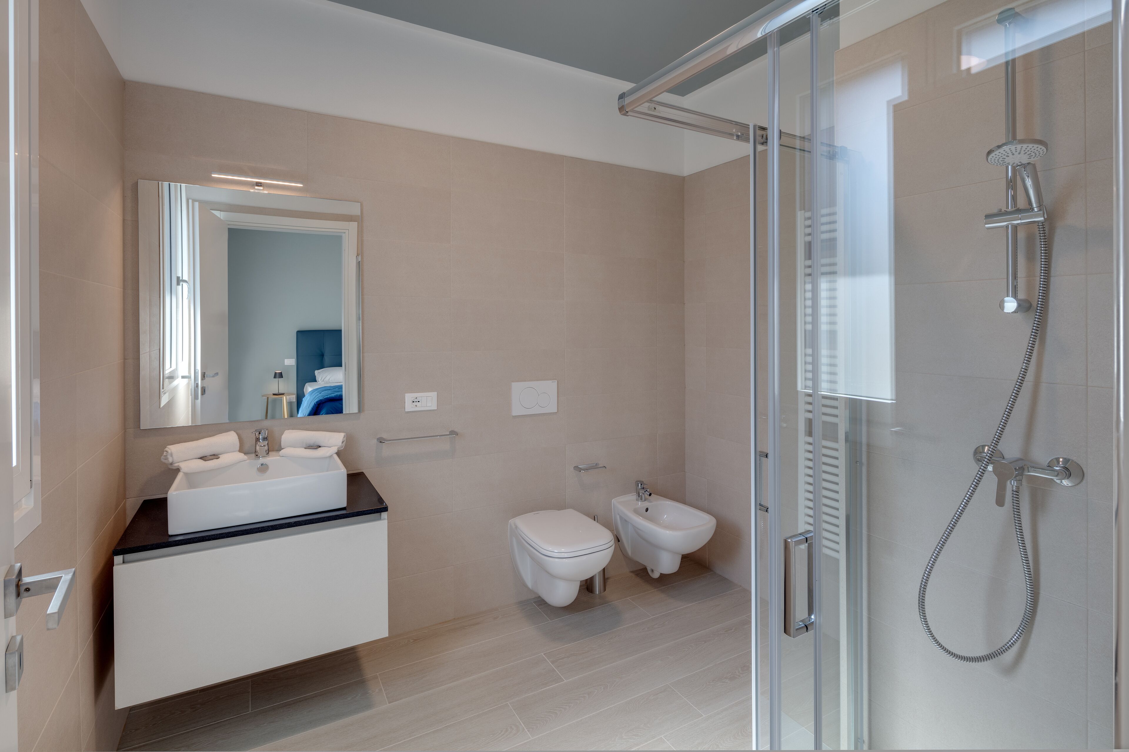 Un baño moderno con cabina de ducha de vidrio, un lavamanos blanco y un bidé.