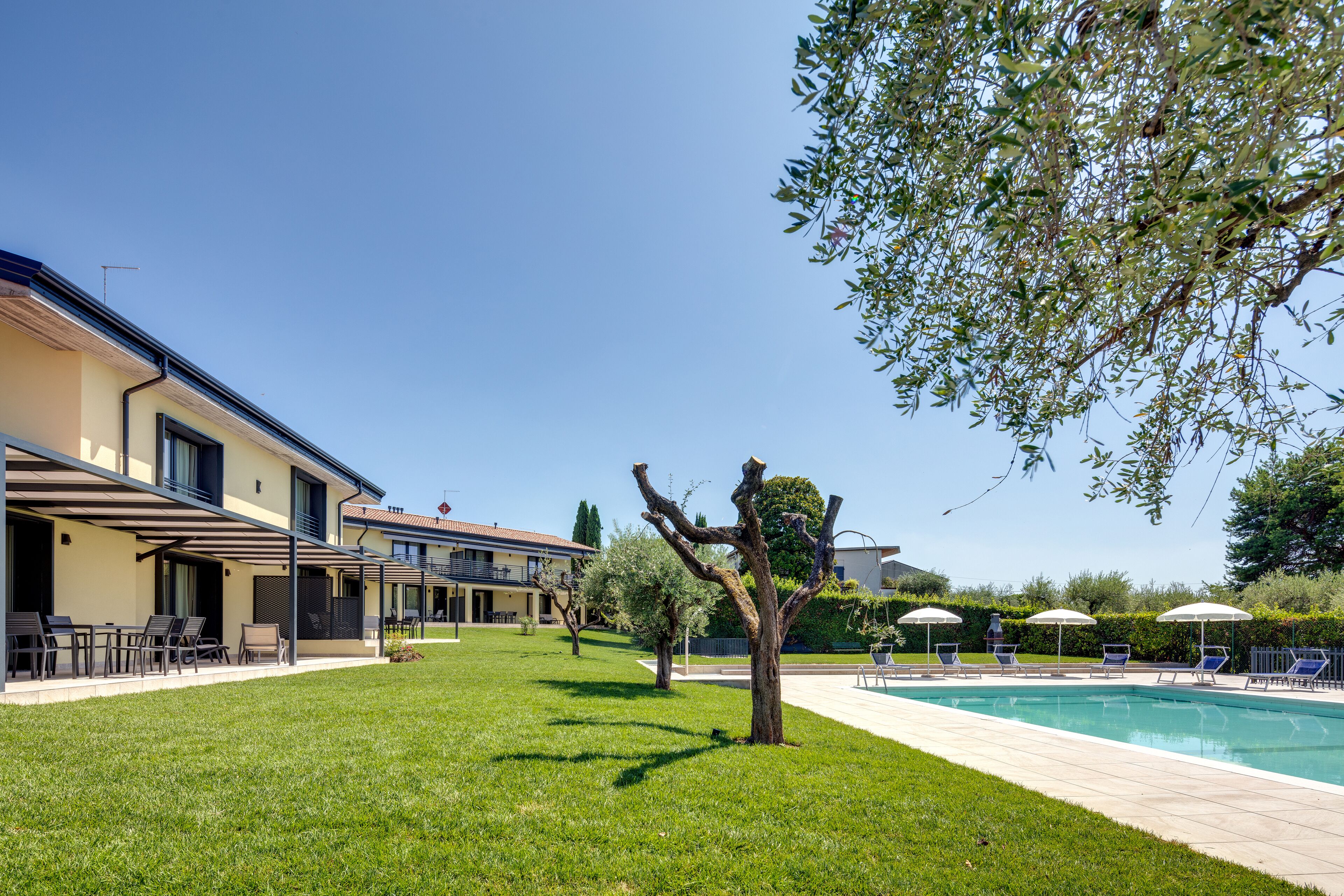 Un área junto a la piscina con sillas de descanso y sombrillas.