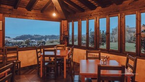 A wooden interior with large windows, a brick fireplace, and a view of the landscape. - Paraje del Asturcón Adults Only (Ribadesella)