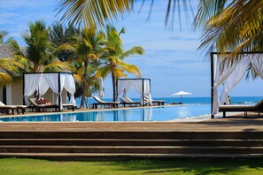 Ein Poolbereich mit Liegestühlen und Blick auf das Meer.