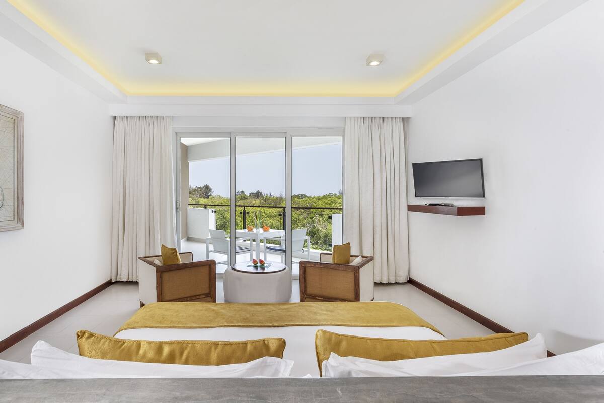 Een moderne hotelkamer met een groot bed, een balkon met een tafel en stoelen, een flatscreen televisie en een kaart aan de muur.