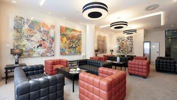 Un espace de détente moderne, avec des canapés en cuir, des œuvres d’art abstraites aux murs et des luminaires contemporains.