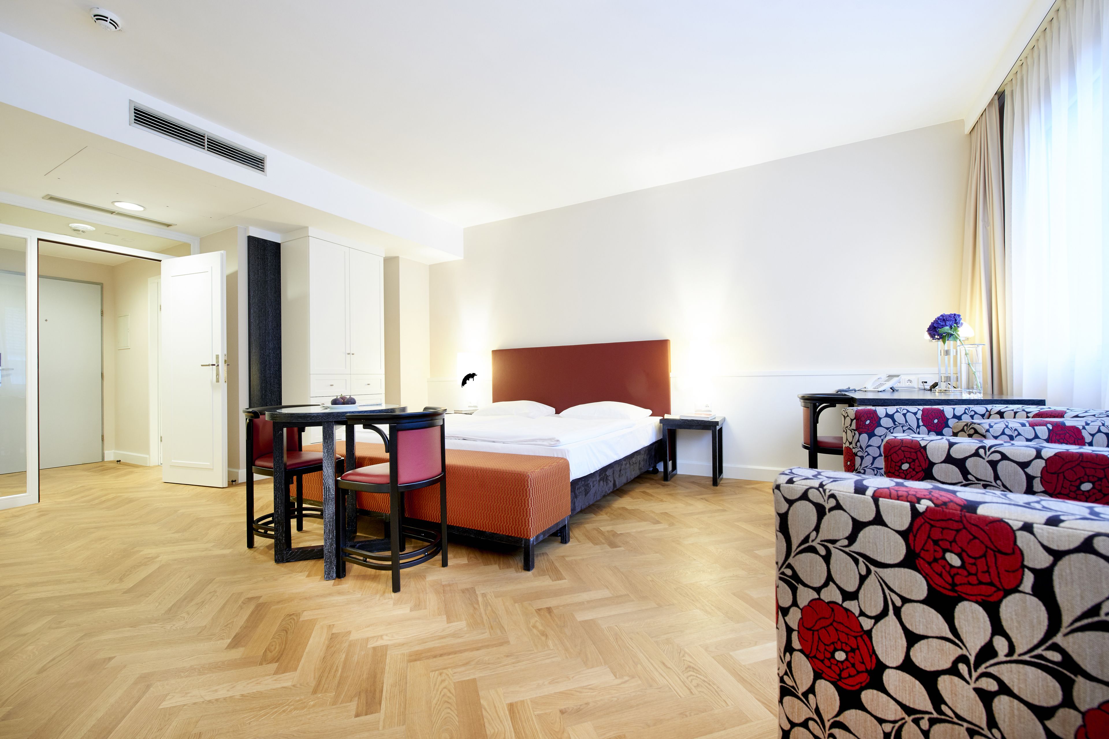 Una habitación de hotel con cama, escritorio, silla, mesita y sofá.