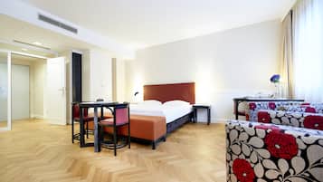 Una habitación de hotel con cama, escritorio, silla, mesita y sofá.