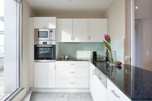 Cocina moderna con armarios blancos, encimera negra y una ventana.