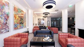 A modern lobby with leather sofas, a glass coffee table, and abstract art on the walls.